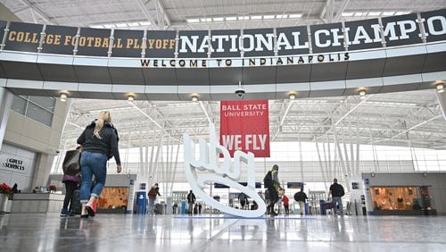 Travelers pass by national championship displays at Indianapolis International Airport on Thursday. Downtown Indianapolis is set to host the 2022 College Football Playoff title game between Georgia and Alabama. (Hyosub Shin / Hyosub.Shin@ajc.com)