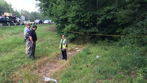 Police investigate the scene where a human skull and bones were found in a suitcase in a wooded area next to an interstate in Gwinnett County (Credit: Gwinnett County Police Department).