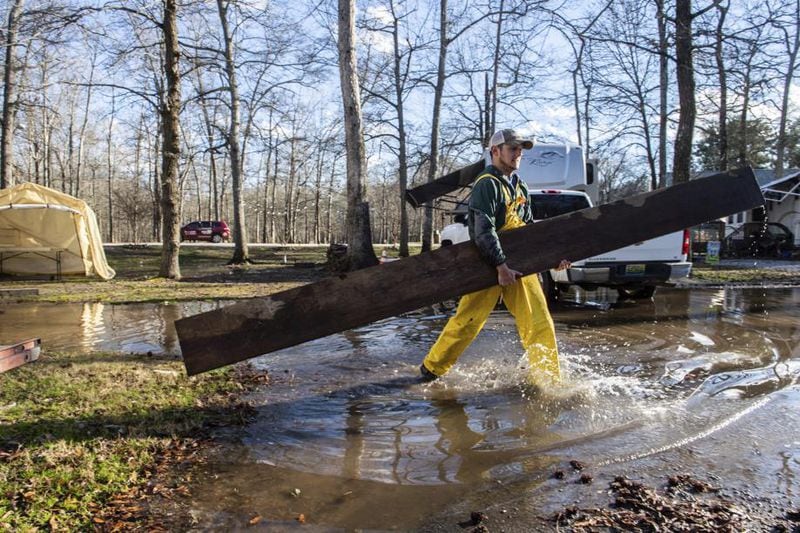 Bradley Foster carries a wooden plank to help a neighbor move their camper from flooding conditions at Point Mallard campground in Decatur, Ala. The Deep South continued to battle flooding Tuesday.