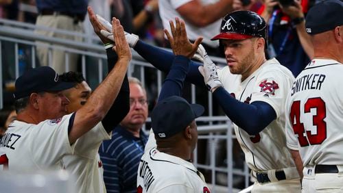 Atlanta Braves' Freddie Freeman (5), second from right, is greeted as he returns to the dugout after hitting a three-run home run in the seventh inning of a baseball game against the Miami Marlins, Saturday, Aug. 5, 2017, in Atlanta. (AP Photo/John Bazemore)