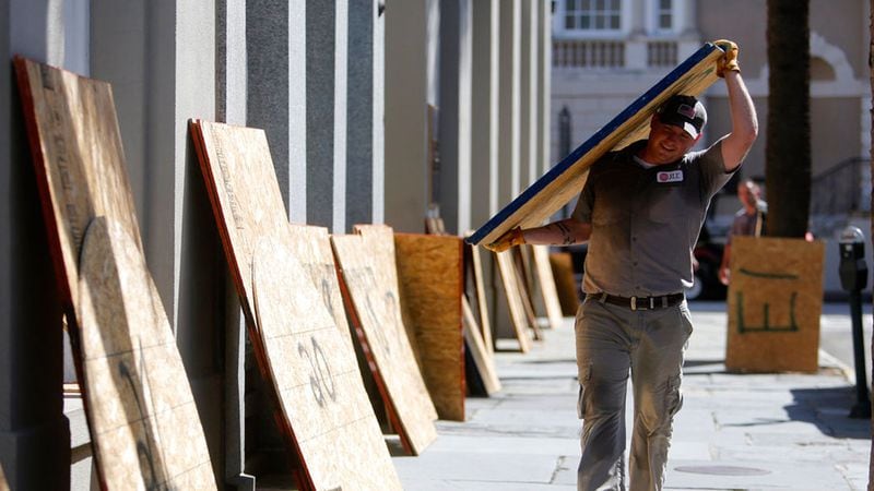 Preston Guiher carries a sheet of plywood as he prepares to board up a Wells Fargo bank in preparation for Hurricane Florence in downtown Charleston, S.C., Tuesday, Sept. 11, 2018.