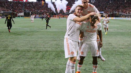 August 19, 2018 Atlanta: Atlanta United forward Josef Martinez (right) celebrates with Franco Escobar and Miguel Almiron on his back after making the MLS season record tieing goal, his 27th, past Columbus Crew defender Jonathan Mensah for a 1-0 lead during the first half in a MLS soccer match on Sunday, August 19, 2018, in Atlanta. The Atlanta United won the game 3-1. Curtis Compton/ccompton@ajc.com