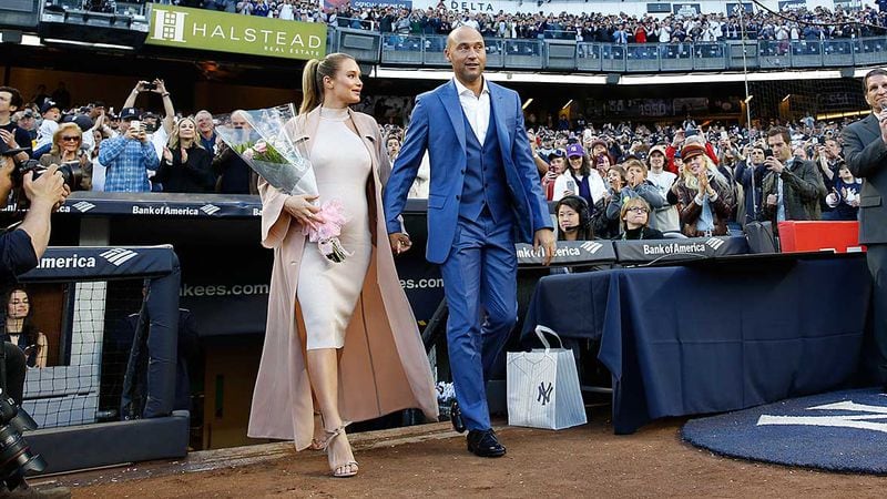 Derek Jeter and wife Hannah walk from the dugout to the field during a pregame ceremony retiring Jeter's number 2 in Monument Park at Yankee Stadium Sunday.