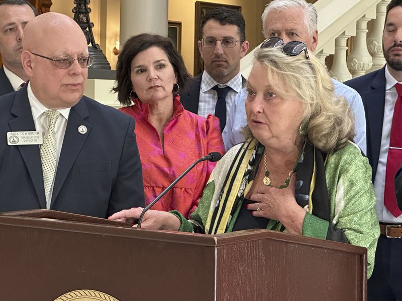 As state Rep. Rick Townsend looks on, Anne Rogers speaks at a news conference at the Georgia Capitol on Thursday, May 2, 2024, after Gov. Brian Kemp signed a bill to regulate kratom. Extracted from the leaves of a tropical tree native to Southeast Asia, kratom is used to make capsules, powders and liquids. It's often sold in gas stations or smoke shops, marketed as an aid for pain, anxiety and drug dependence. Townsend sponsored the bill to increase regulations on kratom after getting a call from Rogers, who said her son Wes died after taking kratom. (AP Photo/Kate Brumback)