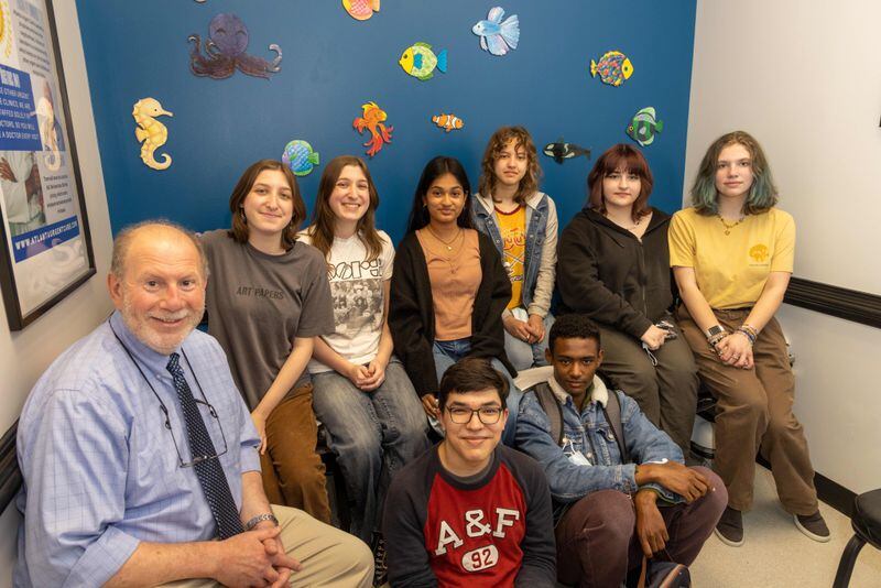 Lakeside High School Art Club members (clockwise from left) teacher Ken Schwager, Lily Toll, Chloe Toll, Nysa Talukder, Madison Maida, Cloud Biccum, Alexis Taylor, Haaven Siye & Svend Halvorsen with the wall of sea creatures they made on display in a pediatric exam room at the Atlanta Urgent Care nearby. PHIL SKINNER FOR THE ATLANTA JOURNAL-CONSTITUTION