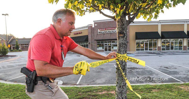 Clayton County police Lt. Thomas Reimers takes down yellow tape at the scene of a deadly shooting. JOHN SPINK / JSPINK@AJC.COM