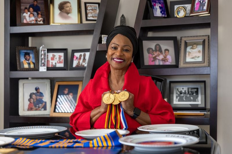 Deborah Evans poses with International Culinary Olympics medals and other award plates won by her late husband, chef Darryl Evans, at her home in Stone Mountain on Thursday, February 15, 2024. (Arvin Temkar / arvin.temkar@ajc.com)