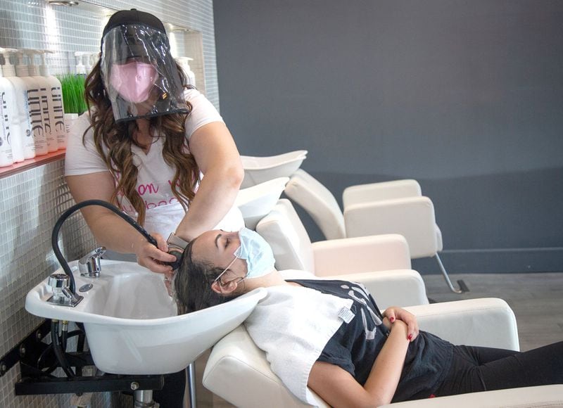 Blo Blow Dry Bar district manager Maria Dowling wears a face shield and a mask while working on Sara Askari’s hair at the Buckhead location Thursday, July 2, 2020 STEVE SCHAEFER FOR THE ATLANTA JOURNAL-CONSTITUTION