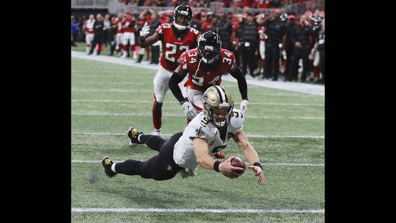               New Orleans Saints quarterback Drew Brees dives into the end zone past Atlanta Falcons defenders Brian Poole and Robert Alford on a quarterback keeper to tie the game 37-37 in the fourth quarter and send it to overtime, during an NFL football game, Sunday, Sept 23, 2018, in Atlanta. New Orleans went on to win 43-37 in overtime. (Curtis Compton/Atlanta Journal-Constitution via AP)             