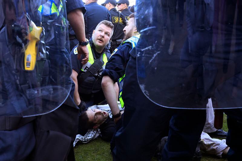 Police detain a demonstrator protesting the war in Gaza as they work to remove a non-sanctioned encampment on the campus of UW-Madison in Madison, Wis., on Wednesday, May 1, 2024. (John Hart/Wisconsin State Journal via AP)