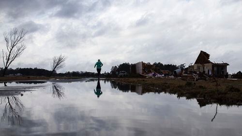 Marilyn Bullard makes her way to a home that was damaged by a tornado, Sunday, Jan. 22, 2017, in Adel, Ga. (AP Photo/Branden Camp)