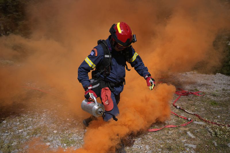 A member of the 1st Wildfire Special Operation Unit, holds drip torch used to scorch strips of earth and create fire breaks, during a drill near Villia village some 60 kilometers (37 miles) northwest of Athens, Greece, Friday, April 19, 2024. Greece's fire season officially starts on May 1 but dozens of fires have already been put out over the past month after temperatures began hitting 30 degrees Celsius (86 degrees Fahrenheit) in late March. This year, Greece is doubling the number of firefighters in specialized units to some 1,300, adopting tactics from the United States to try and outflank fires with airborne units scrambled to build breaks in the predicted path of the flames. (AP Photo/Thanassis Stavrakis)