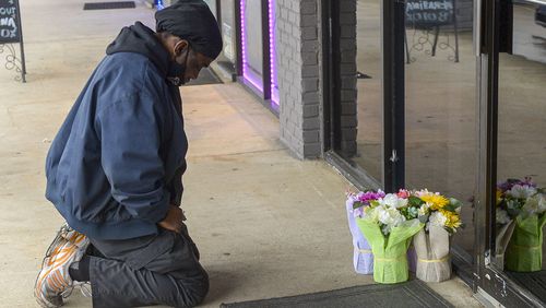 Acworth resident Derrick Franklin places flowers near the entrance of Youngs Asian Massage Parlor Wednesday, March 17 2021 in Cherokee County. Franklin, who works nearby in Woodstock, did not know the owners but came to pay his respects after a shooting that left four people dead and one injured at the massage parlor. (PHOTO/Daniel Varnado) 
