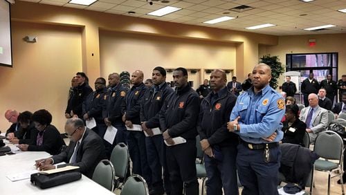 Firefighters stand together as they seek pay increases during the DeKalb County Board of Commissioners meeting Tuesday. County commissioners are also asking for a pay raise for themselves. MARK NIESSE / MARK.NIESSE@AJC.COM