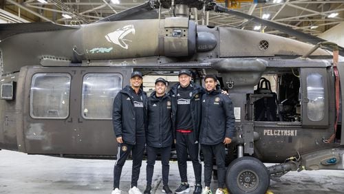 Atlanta United players Miles Robinson, Brooks Lennon, Brad Guzan and Caleb Wiley pose in front of a Black Hawk helicopter at Fort Bragg in North Carolina on Tuesday. (USO photo)