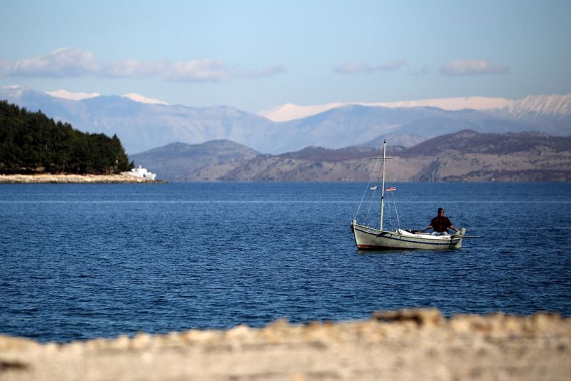 A fisherman steers his boat along the shoreline in Corfu, Greece.
