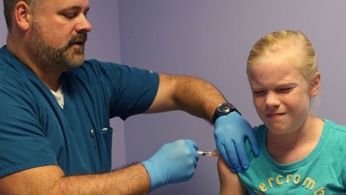 Elizabeth Plyler gets a flu shot from Greg Wicker, a registered medical assistant at Dunwoody Pediatrics. The 10 year-old spent four days in ICU after coming down with the flu. Although flu season didn't officially begin until October, doctors are already diagnosing the virus in metro Atlanta children.