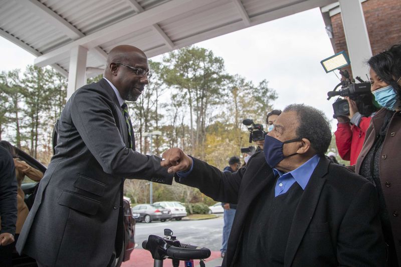 Democratic U.S. Senate candidate Rev. Raphael Warnock greets former Mayor of Atlanta and United Nations Ambassador Andrew Young (right) during early voting at the C.T. Martin Natatorium and Recreation Center near the Westhaven neighborhood in Atlanta on December 14, 2020.  (Alyssa Pointer / Alyssa.Pointer@ajc.com)