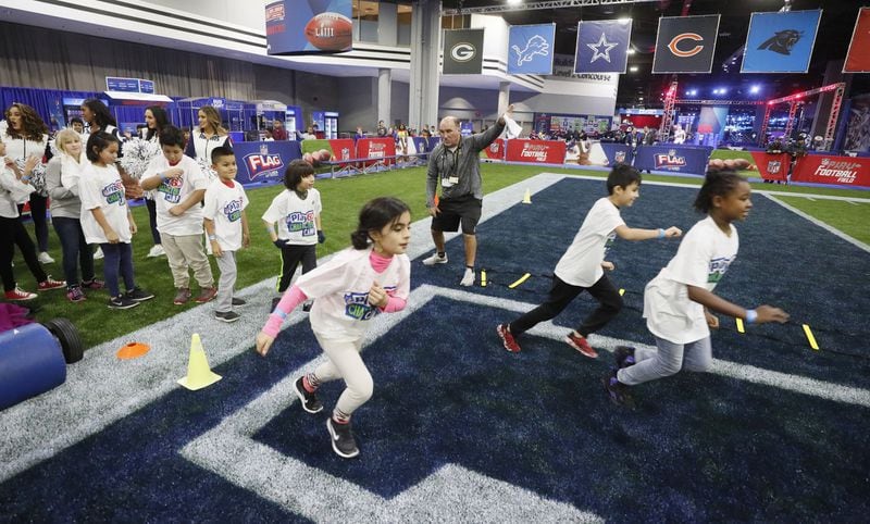 Kids from two metro area schools run onto the field to meet their designated coaches at the start of the NFL’s Play60 Character Camp. During Super Bowl Week, the NFL hosts PLAY 60, a national youth health and fitness campaign focused on encouraging kids to be active for at least 60 minutes a day. The event on Monday led by Pro Football Hall of Fame offensive tackle Anthony Muñoz hosted 300 mostly Hispanic children for an activity session. (Bob Andres / bandres@ajc.com)