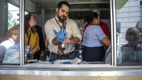 Gary Coggins (center) puts on gloves before conducting environmental sampling on a food truck at the Association of Food and Drug Officials eductional conference at the Grand Hyatt Atlanta in Buckhead,  on Saturday, June 22, 2019.  (Photo: BRANDEN CAMP/SPECIAL TO THE AJC)