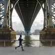A runner makes his way along the East River as he passes under the Manhattan Bridge in New York on Dec. 4, 2021. The first few weeks of training for a marathon should focus on the basics -- easy pace, weight training and setting your expectations. (Keith E. Morrison/The New York Times)