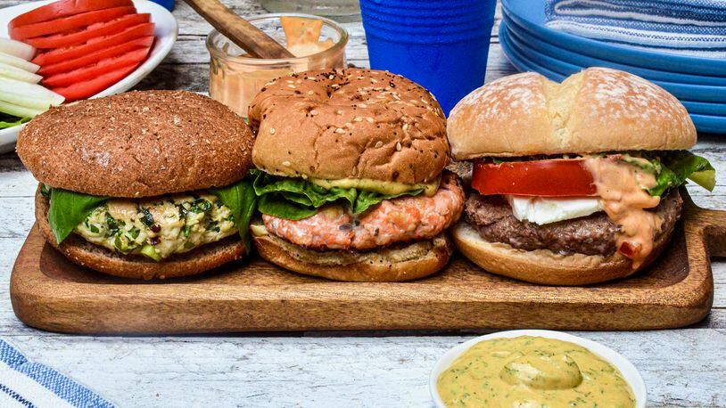 Change your burger routine with a non-beef patty. Pictured, from left to right, are a Blue Cheese-Stuffed Turkey Burger, Salmon Burger with Mustard Dill Sauce, and Lamb Burger with Harissa Mayonnaise. Virginia Willis/For the AJC
(Virginia Willis for The Atlanta Journal-Constitution)