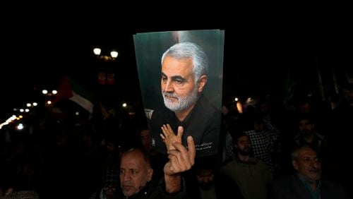 A demonstrator holds up a poster of the late Iranian Revolutionary Guard Gen. Qassem Soleimani, who was killed in a U.S. drone attack in 2020 in Iraq, during an anti-Israeli gathering in front of the British Embassy in Tehran, Iran, early Sunday, April 14, 2024. Iran launched its first direct military attack against Israel on Saturday. (AP Photo/Vahid Salemi)