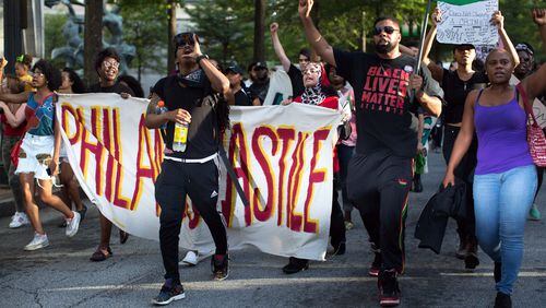 Demonstrators carry signs as they march down Peachtree Street to Piedmont Park, Thursday, July 7, 2016, in Atlanta. Demonstrators gathered in response to the death of 37-year-old Alton Sterling, who was killed by Baton Rouge police outside of a convenience store where he was selling CDs and Philando Castile, who was shot and killed when Minnesota police stopped him for a traffic violation on Wednesday evening. BRANDEN CAMP/SPECIAL