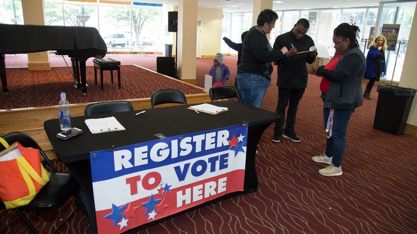 Volunteer Cylinda Parga, left, helps high school student Joshua McBrewer fill out his voter registration application before the start of the Town Hall For Our Lives in April in Atlanta. STEVE SCHAEFER / SPECIAL TO THE AJC