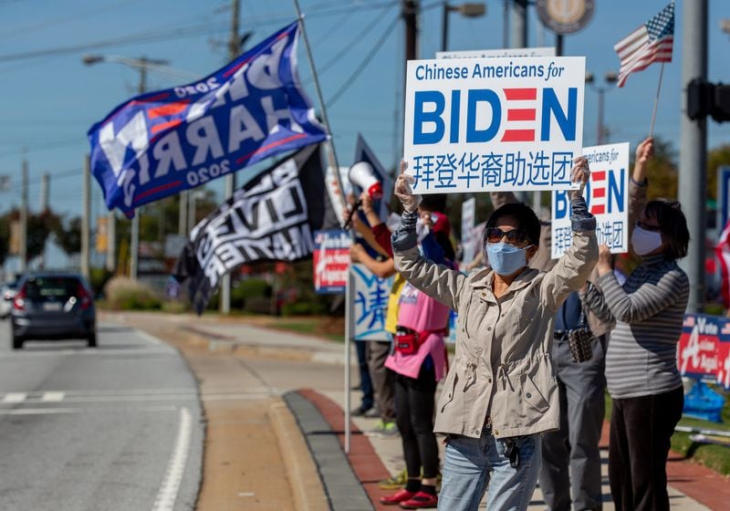 Annie Qian holds up a sign on Pleasant Hill Rd Saturday during a Chinese for Biden rally on October 17, 2020.  STEVE SCHAEFER / SPECIAL TO THE AJC 