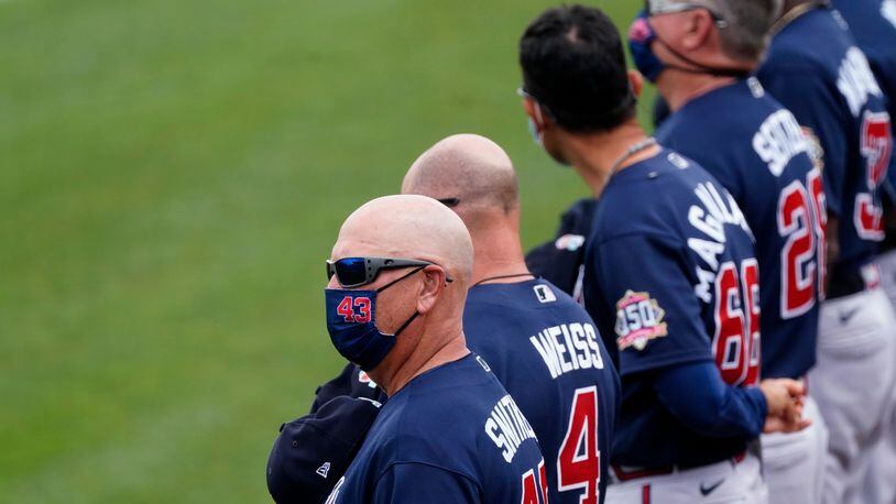 Atlanta Braves manager Brian Snitker (43) stands for the national anthem with his players and coaches before a spring training game Monday, March 22, 2021, against the Minnesota Twins in Fort Myers, Fla. (John Bazemore/AP)