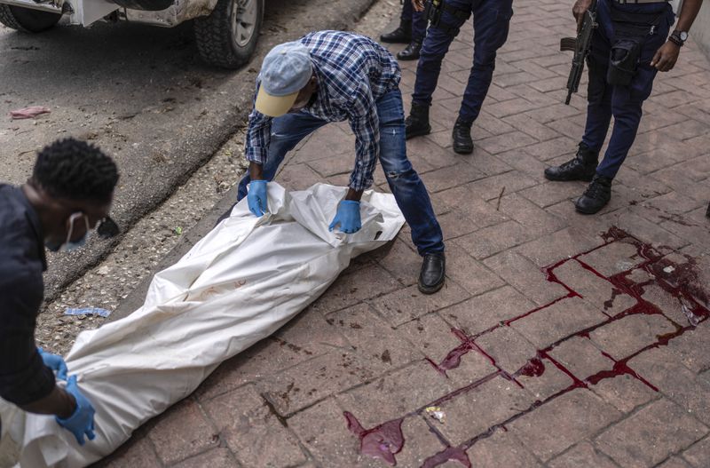 Forensic workers remove the body of a man shot dead in the Petion-Ville neighborhood of Port-au-Prince, Haiti, Friday, May 3, 2024. (AP Photo/Ramon Espinosa)