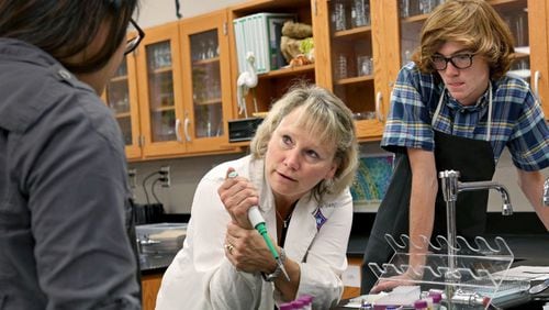 Walton High School Advanced Placement Biology teacher Tina Link, center, demonstrates how to steady her hand while using a micro pipette to students in 2014. Walton earned the No. 7 spot on Niche’s ranking of 2017’s best high schools in Georgia.