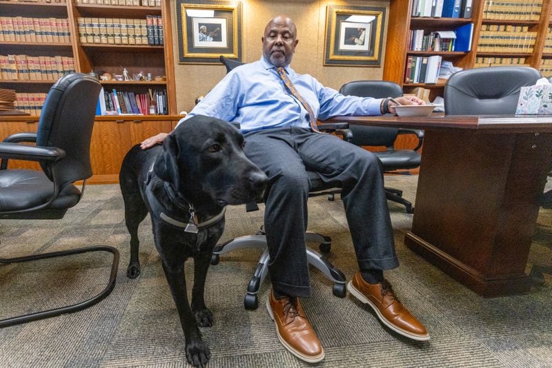 Chief Judge Ural Glanville sits in his Fulton County courtroom office with his service dog, Jack.
