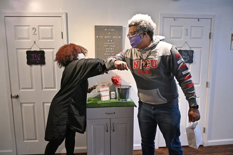 Nekesa Smith, a local stylist and hair expert, and AJC reporter Ernie Suggs bump elbows after she gave him an advice about his hair and growing an Afro at her shop in College Park on Friday, Feb. 12, 2021. (Hyosub Shin / Hyosub.Shin@ajc.com)