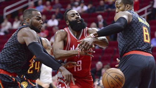 Houston Rockets guard James Harden (13) loses the ball as he drives between Atlanta Hawks forward Paul Millsap, left, and Dwight Howard (8) during the first half of an NBA basketball game Thursday, Feb. 2, 2017, in Houston. (AP Photo/George Bridges)