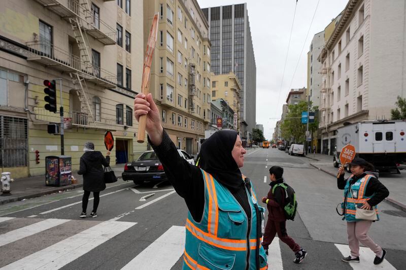 Tatiana Alabsi, center, waits for children to safely cross a street in the Tenderloin neighborhood Wednesday, April 24, 2024, in San Francisco. (AP Photo/Godofredo A. Vásquez)