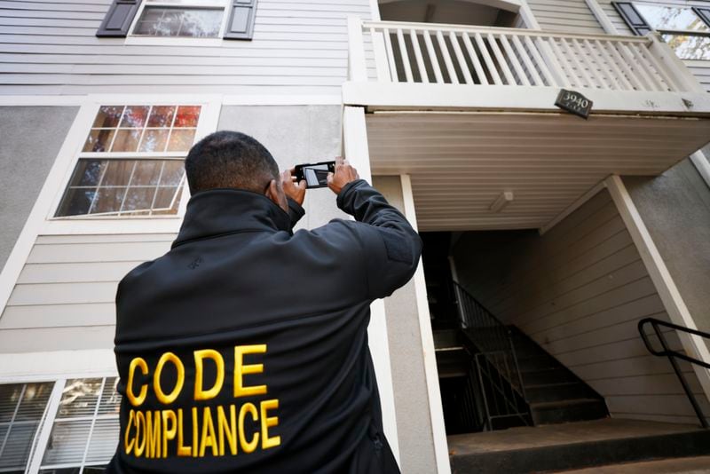 A DeKalb County code compliance supervisor photographs a deteriorating balcony at Woodside Village Apartments near Clarkston in October. An audit issued earlier this year found that the code compliance office has struggled to keep up with complaints. (Miguel Martinez / miguel.martinezjimenez@ajc.com)