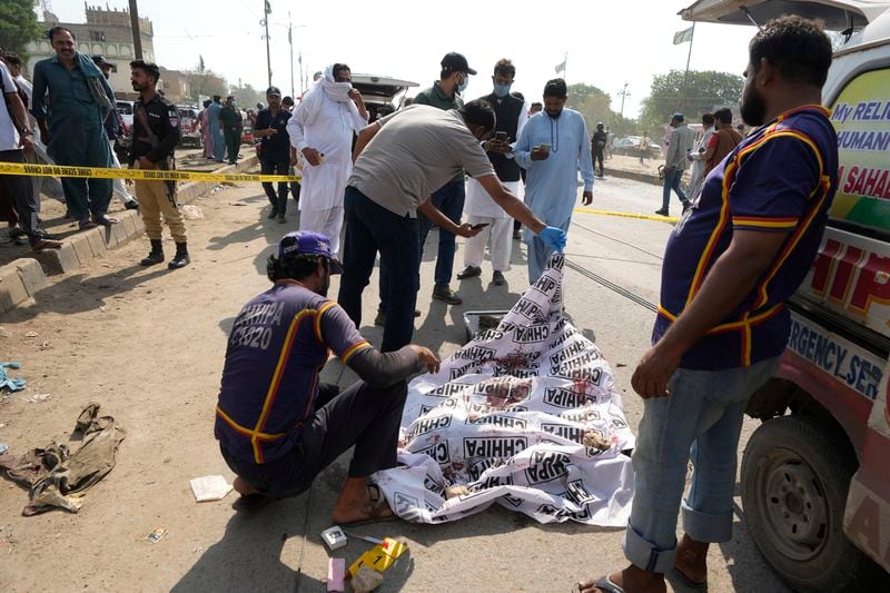 Pakistani investigators take picture of the body of attacker at the site of a suicide attack in Karachi, Pakistan, Friday, April 19, 2024. A suicide bomber detonated his explosive-laden vest near a van carrying Japanese autoworkers, who narrowly escaped the attack Friday that wounded three bystanders in Pakistan's port city of Karachi, police said.(AP Photo/Fareed Khan)