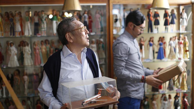 In this Jan. 6, 2017 photo, the founder of the Mexico Antique Toy Museum, Roberto Shimizu, left, and his son, Roberto, arrange objects prior to the opening of a temporary Barbie Doll exhibit in Mexico City. Even as a child, Roberto Shimizu loved collecting things. So when his Japanese immigrant father opened a stationary and toy store in the Mexican capital in 1940, Shimizu began a lifelong quest to save and collect toys. More than seven decades years later that youthful fascination lives on the Antique Toy Museum, a four-story building packed with objects that take transport visitors back to a nostalgic past. (AP Photo/Dario Lopez-Mills)