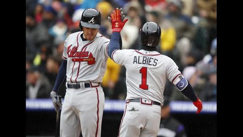 Atlanta Braves' Freddie Freeman, left, congratulates Ozzie Albies who crosses home plate after hitting a solo hoe run off Colorado Rockies starting pitcher German Marquez in the first inning of a baseball game Friday, April 6, 2018, in Denver. (AP Photo/David Zalubowski)