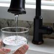 A file photo shows tap water filling a glass. The north Georgia city of Calhoun, which has been home to flooring and carpet manufacturing for decades, is facing multiple lawsuits alleging sewage sludge from its wastewater treatment plant has contaminated land and water in the area with toxic “forever chemicals.” (Justin Sullivan/Getty Images/TNS)