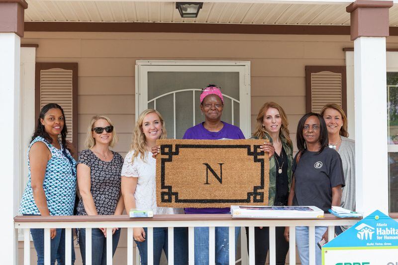 Volunteers present Jamilah Najeeullah with a doormat bearing her last initial at her new home. Najeeullah is among nearly 50 families who received homes with help from Atlanta Habitat for Humanity. CONTRIBUTED