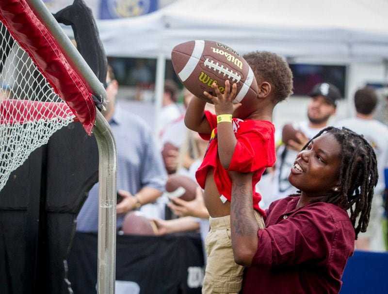 Jassmine Calhoun holds her son Jmankis Jennings, 2, while he throws a football into a large net during the Inaugural SEC Summerfest in Centennial Olympic Park on Sunday, July 15, 2018. (Photo: STEVE SCHAEFER / SPECIAL TO THE AJC)