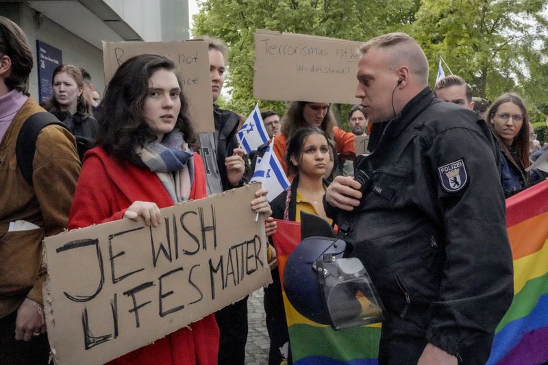 A woman carries a sign reading "Jewish life matters" when facing a pro-Palestinians demonstration by the group "Student Coalition Berlin" in the theater courtyard of the 'Freie Universität Berlin' university in Berlin, Germany, Tuesday, May 7, 2024. Pro-Palestinian activists occupied a courtyard of the Free University in Berlin on Tuesday. (AP Photo/Markus Schreiber)