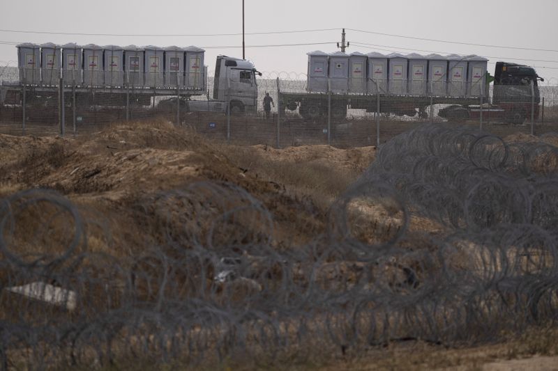 Trucks, carrying humanitarian supplies for the Gaza Strip, wait in line on the Egyptian side, at the Kerem Shalom Crossing border as seen from southern Israel, Thursday, April 25, 2024. (AP Photo/Leo Correa)
