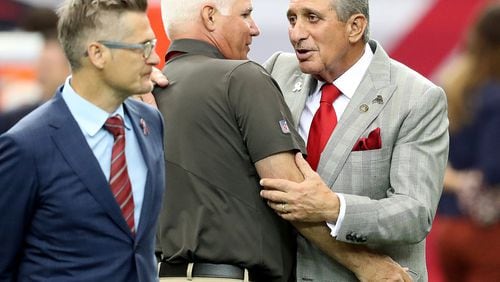 Former Falcons head coach Mike Smith gets a hug from Arthur Blank after speaking with Thomas Dimitroff before Tampa Bay’s game in the Georgia Dome on Sept. 11. Curtis Compton /ccompton@ajc.com