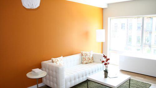 A rich orange accent wall serves as a backdrop in this minimal and modern living space. (Design Recipes)