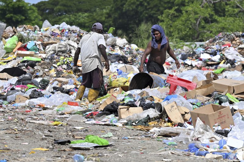 Residents who live on the Ranadi Landfill site scavenge through the rubbish in Honiara, Solomon Islands, Sunday, April 14, 2024. The country in which China has gained most influence in the South Pacific, Solomon Islands, goes to the polls on Wednesday in an election that could shape the region's future. (Mick Tsikas/AAP Image via AP)
