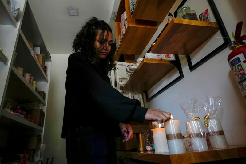A woman lights candles in her store after a programed power cut by the ministry of energy, in Quito, Ecuador, Tuesday, April 16, 2024. Ecuador faces electricity rationing due to a prolonged drought and high temperatures that have reduced flows to the main hydroelectric plants. (AP Photo/Dolores Ochoa)